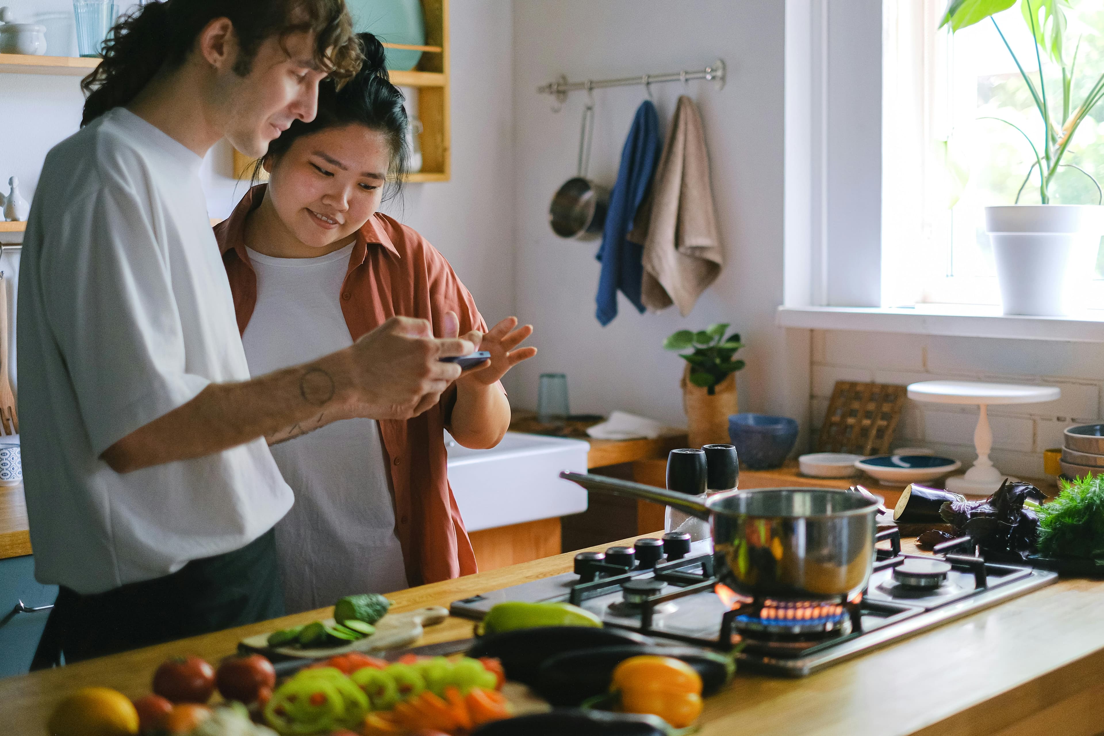 Two people coordinating cooking plans together on a phone in the kitchen.